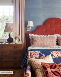 a bedroom with a red headboard, blue walls and floral bed linens on the bed