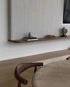 a flat screen tv mounted to the side of a wall next to a wooden table