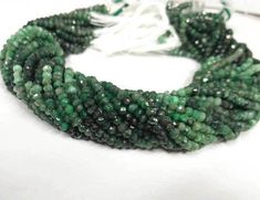 green and black beads are arranged together on a white surface with a string attached to it