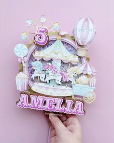 someone holding up a pink and white card with an image of a carousel