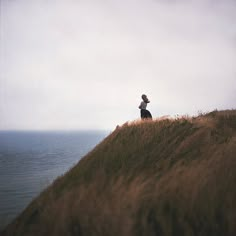 a person standing on top of a grass covered hill