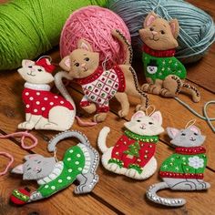 several knitted ornaments are sitting on a wooden table with yarn and balls of yarn in the background