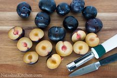 some plums and a knife on a cutting board