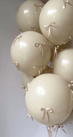 a bunch of white balloons with bows tied around them on top of each other in a vase