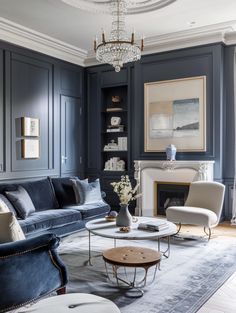 a living room filled with furniture and a chandelier hanging from the ceiling over a fire place