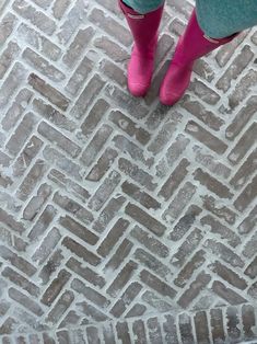 a person in pink boots standing on a brick floor