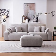 a living room with a couch, ottoman and rug on the wooden floor in front of it