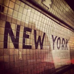 the words new york are written in black and white on a mosaic tile wall above a subway entrance