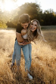 a man and woman hugging in the middle of a field