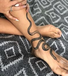 a woman's foot with a snake tattoo on the side of her leg and hands