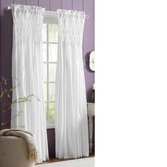 a living room with purple walls and white curtains