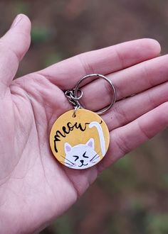 a hand holding a keychain with a cat on it