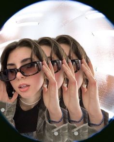 three women wearing sunglasses are looking in the mirror and holding their hands to their face