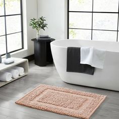 a white bath tub sitting in a bathroom next to a window with lots of windows