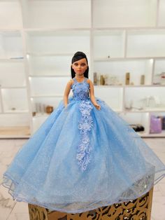 the doll is wearing a blue dress with flowers on it's skirt and standing on top of a cake