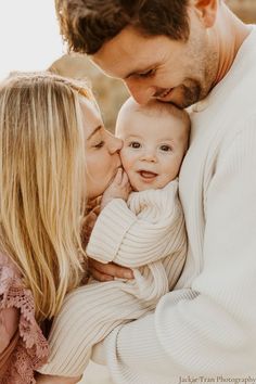 a man and woman holding a baby in their arms