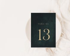 a table number card with the number thirteen printed on it in gold and dark green