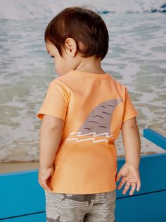 This sweet baby shark is a good reminder that most are friendly to humans. This back-to-front tee is set against a summery cantaloupe background and pairs beautifully with a shorts. Above thigh length. 100% soft cotton jersey. Standard fit Crew neckline Short sleeve Above thigh length 100% cotton jersey Machine wash Baby Graphic Tees, Kids Boutique, Tea Collection, Baby Shark, Baby Boutique, Soft Shorts, Newborn Baby, Childrens Clothes, Labour Day