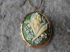 "Beautiful cameo locket The cameo is a gorgeous lily of the valley on your choice of backgrounds, green, lavender/purple, and black, also hand painting is available The gold plated locket is victorian style with beautiful etching on both the front and back, measuring 2\" long. It can hold two photos and/or treasured keepsakes Pass down from generation to generation The chain is 22\" 1.2mm gold plated snake chain with a lobster claw clasp Perfect for brides or bridal parties. Makes a unique memor Backgrounds Green, Creepy Baby Dolls, Kintsugi Art, Cameo Pendant Necklace, Green Lavender, Scary Dolls, Yule Ball, Bride Hair Accessories, Bridal Parties