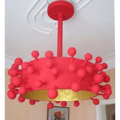 a red and gold chandelier hanging from the ceiling in a room with pictures on the wall