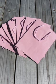 four pieces of pink paper sitting on top of a wooden table