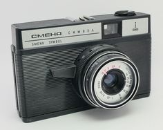 an old camera with a lens attached to the front and side, sitting on a white surface