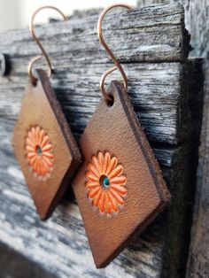 Beautifully dyed pair of floral earrings in warm colors of caramel, tobacco, and orange. Crafted by hand from start to finish, these earrings start out as blank slates of premium veg-tanned leather. From there, I hand-tool, dye, and paint each pair. As with most artisan jewelry, no two sets are alike. All leather pieces are conditioned with beeswax, which keeps leather supple and water resistant (see video). Edges and backs are conditioned and finished, as well. Please remember that time and wea Bohemian Orange Copper Earrings, Orange Copper Bohemian Earrings, Brown Flower Earrings With Ear Wire, Bohemian Brown Flower Jewelry, Unique Brown Earrings For Gift, Vintage Brown Flower-shaped Jewelry, Earthy Brown Drop Earrings, Earthy Brown Copper Earrings, Handmade Vintage Rust-colored Earrings