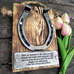 a wooden plaque with a metal horseshoe and flowers