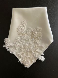 an embroidered white handkerchief on a black surface