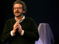 a man standing in front of a white table cloth with his hands folded up to the side