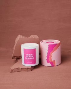 a pink candle sitting on top of a table next to a container