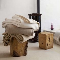 a stack of folded blankets sitting on top of a wooden block next to a bed