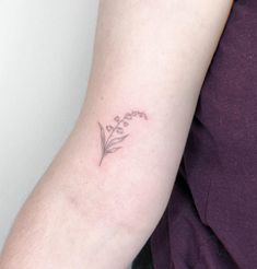 a woman's arm with a small flower tattoo on the left side of her arm