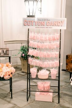 there is a sign that says cotton candy on it and some pink cups in front of it