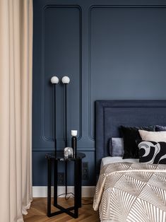 a bedroom with blue walls and wooden flooring, two lamps on each side of the bed