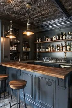 a bar with two stools in front of it and several bottles on the shelves