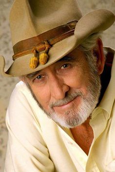 an older man wearing a cowboy hat and looking at the camera with a smile on his face