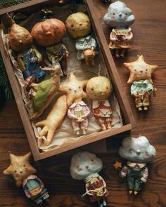 an open box filled with figurines on top of a wooden table next to christmas decorations