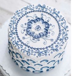 a blue and white decorated cake sitting on top of a white plate with an intricate design