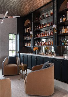 a room with chairs, shelves and bottles on the wall behind it is a bar