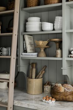 the shelves in this kitchen are filled with dishes and bread