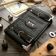 a black leather book sitting on top of a wooden table next to metal objects and other items