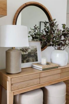 a table with two white stools and a lamp on top of it next to a mirror