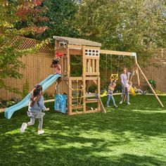 children playing in the backyard with a wooden swing set and climbing frame, while an adult watches