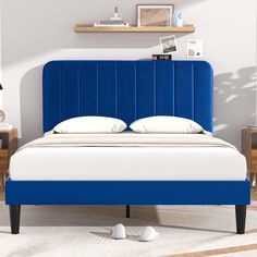 a bed with blue headboard and white pillows in a room next to two nightstands