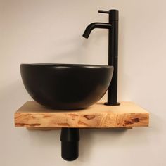 a black bowl sink sitting on top of a wooden shelf