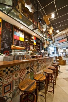 the interior of a restaurant with colorful tiles and wooden stools