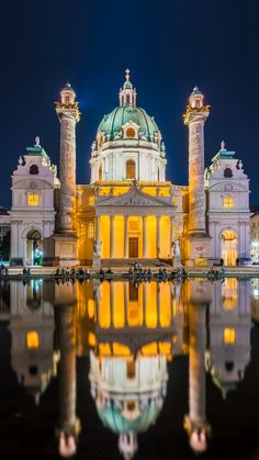 a large building that is lit up at night with its lights on and reflecting in the water