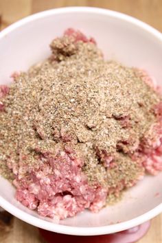 a white bowl filled with ground meat on top of a wooden table