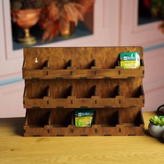 a wooden rack holding several tea bags on top of a table next to a potted plant